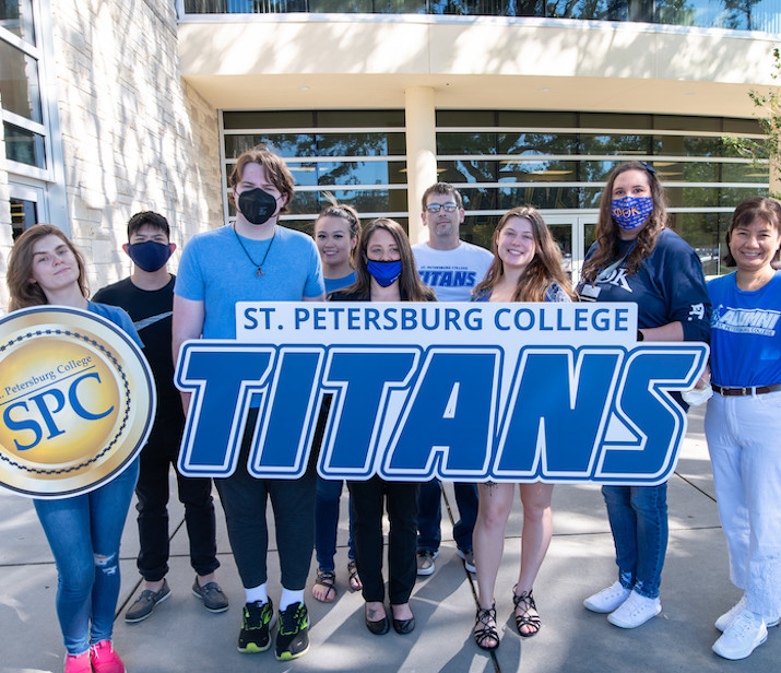 a group of students on campus holding up a Saint Petersburg College Titans banner