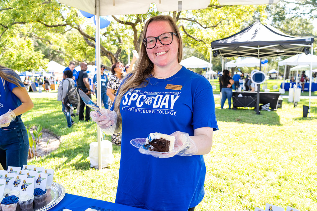 An SPC staff member handing out cake at SPC Day 2023
