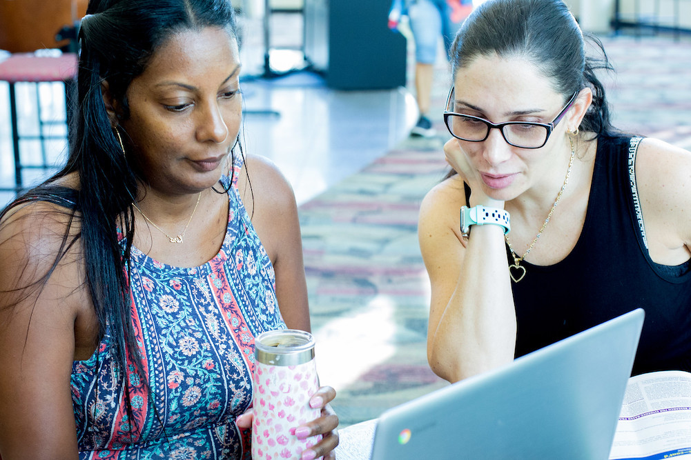 two female students looking at a laptop together at a desk