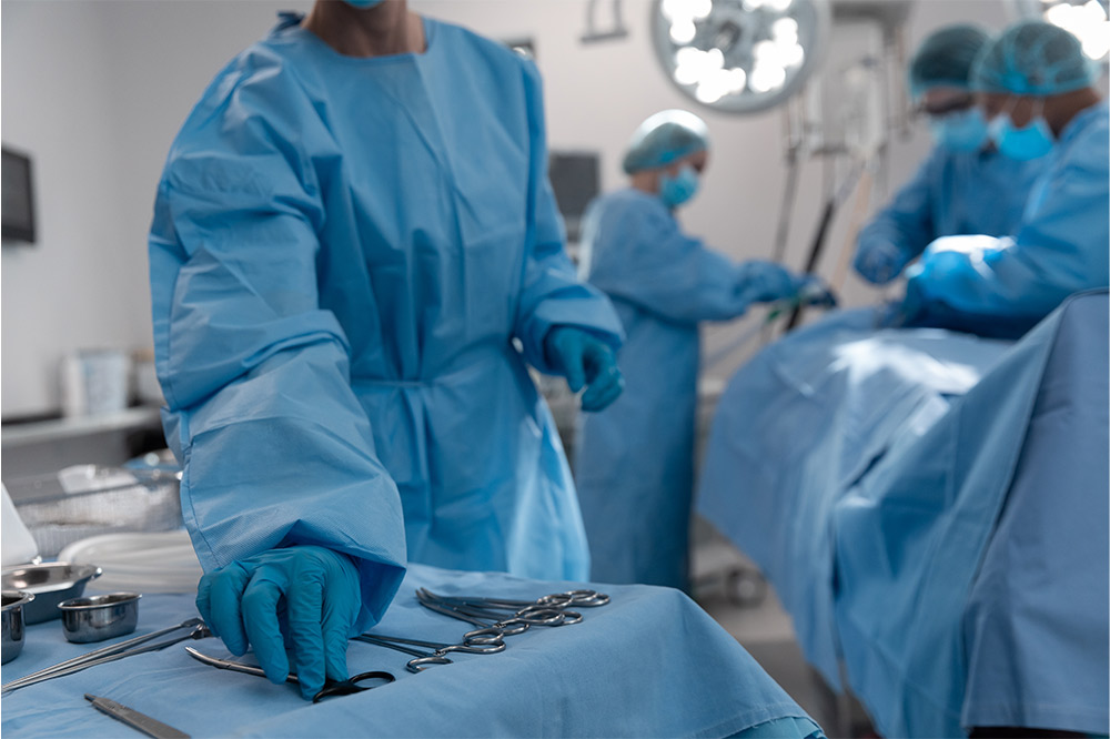 gloved person in scrubs picking up surgical equipment