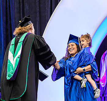 College official wearing a graduation robe shaking 