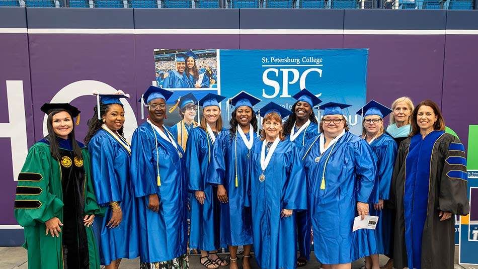 a group of teacher apprentices in blue caps and gowns at graduation