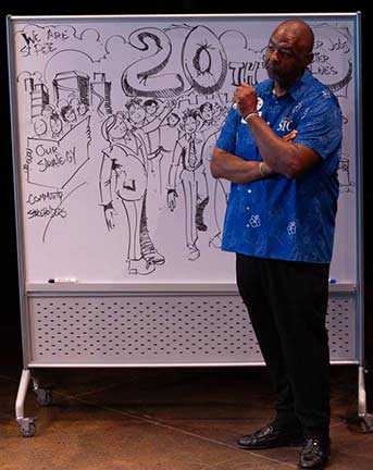 Jonathan Massie standing in front of a white board drawing an illustration