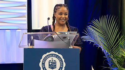portrait of scholarship student Antoinette Catalan standing at a podium addressing donors