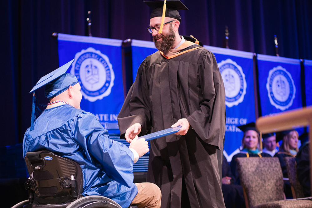 a disabled student receiving their diploma at a graduation ceremony