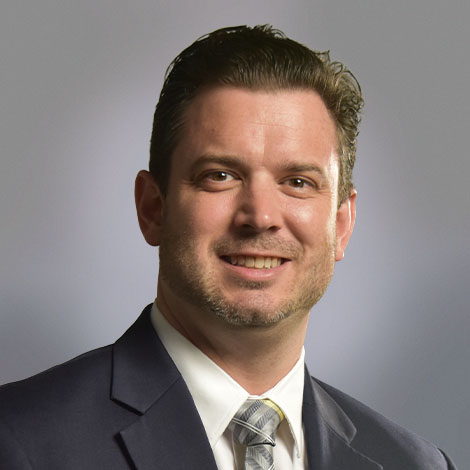 Nicholas Vick dressed in a grey suit with white shirt and tie.