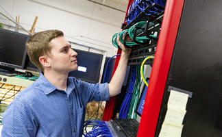 a computer networking student working on a server rack