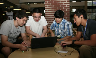 a group of student gathered around a laptop