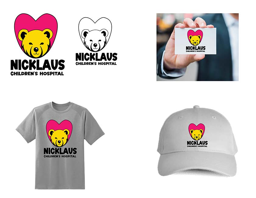 A hand displaying a card for the Nicklaus Children's Hospital with a golden bear face inside of a red heart shape.