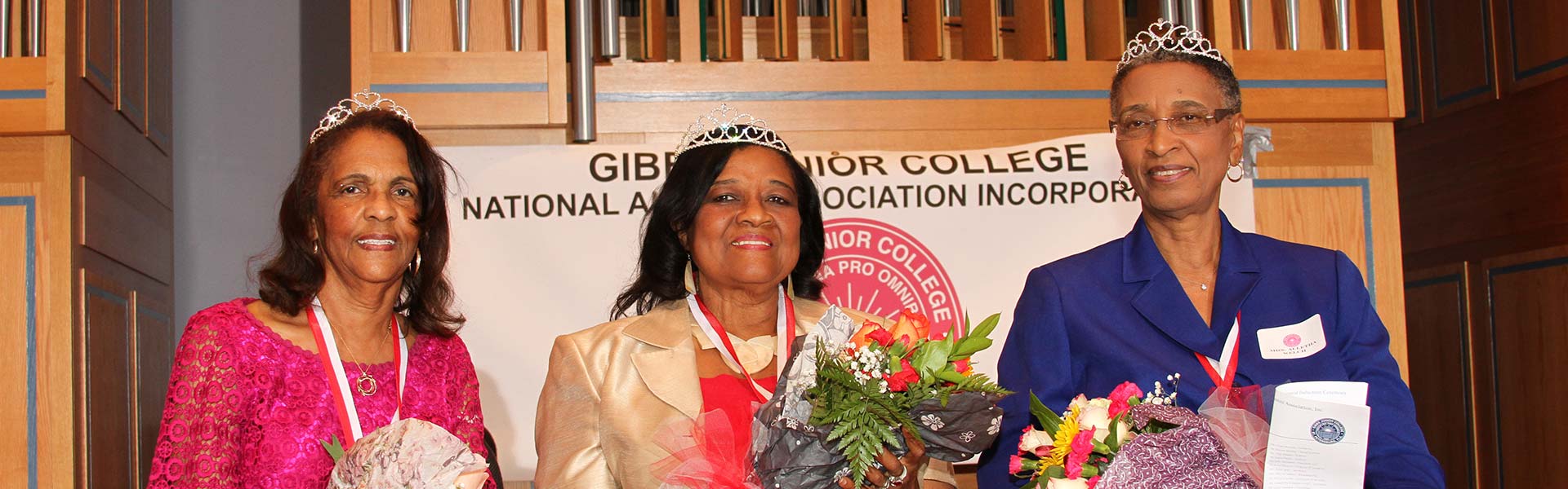 Three Gibbs Junior College Alumni women, each wearing tiaras and holding a bouquet of flowers.