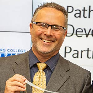 photo of Jeff Mowry wearing a white shirt and tie looking down