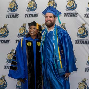 A new SPC graduate poses with SPC President, Dr. Williams, wearing his cap and gown at the graduation ceremony