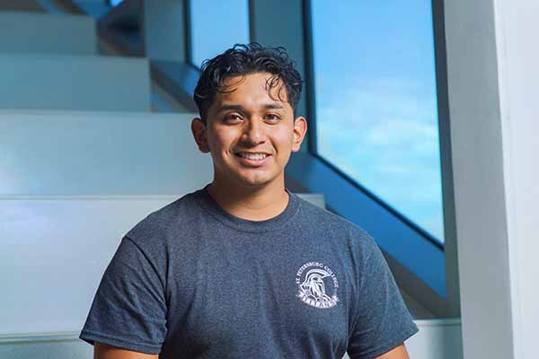 An SPC student sitting on steps inside the Joseph H Lang Student Success Center, wearing his SPC Titans T shirt