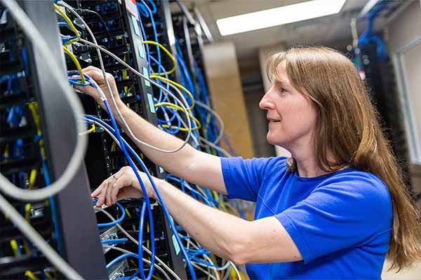 A computer networking student working on server racks