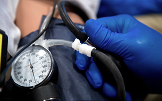 gloved hands manipulating a blood pressure machine