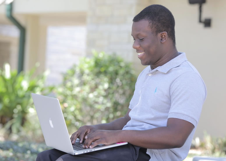 Olabode Opapeju seated outdoors using his laptop