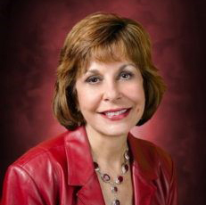 photo of Maria Nieves Edmonds smiling and wearing a red jacket