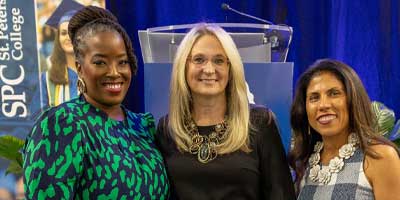 three women of different races posing for a photo dressed formally