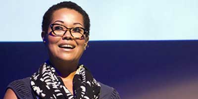 african american woman wearing glasses speaking at a podium