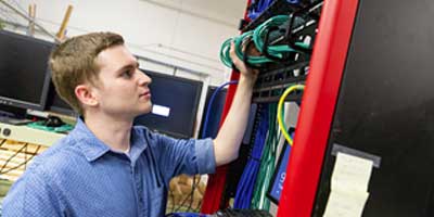 a computer networking student working on a server rack