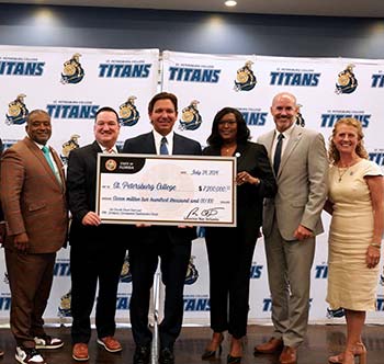 Governor Ron DeSantis holding a large grant check for SPC workforce training, standing with Dr. Tonjua Williams and the SPC Board of Trustees.