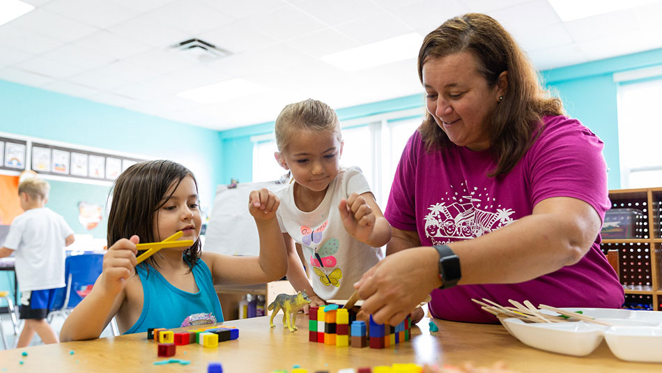 SPC alumna teaching two early child students