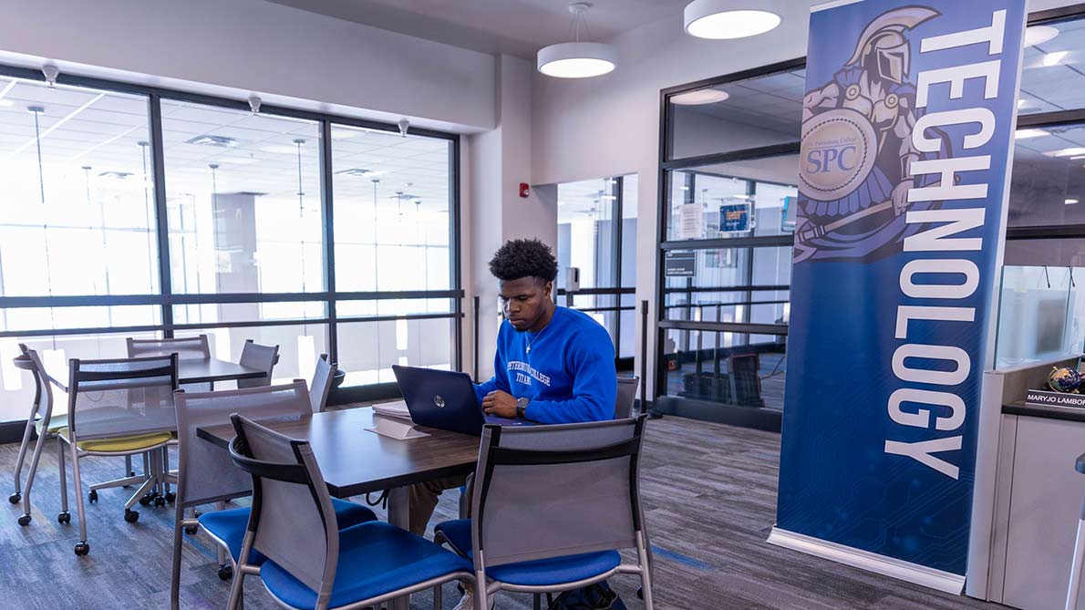 male student sitting at the Downtown Center using a laptop