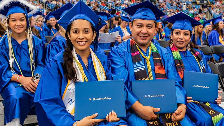 SPC graduates in caps and gowns smiling at commencement