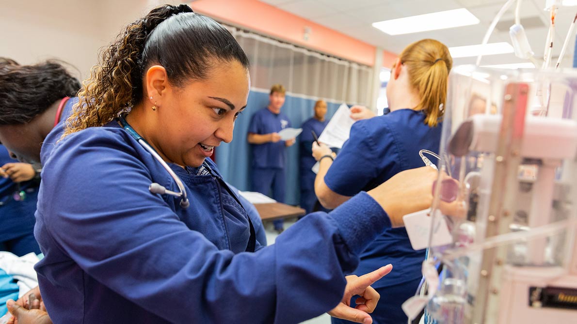 Female nursing student adjusting a monitor in a clincial lab setting