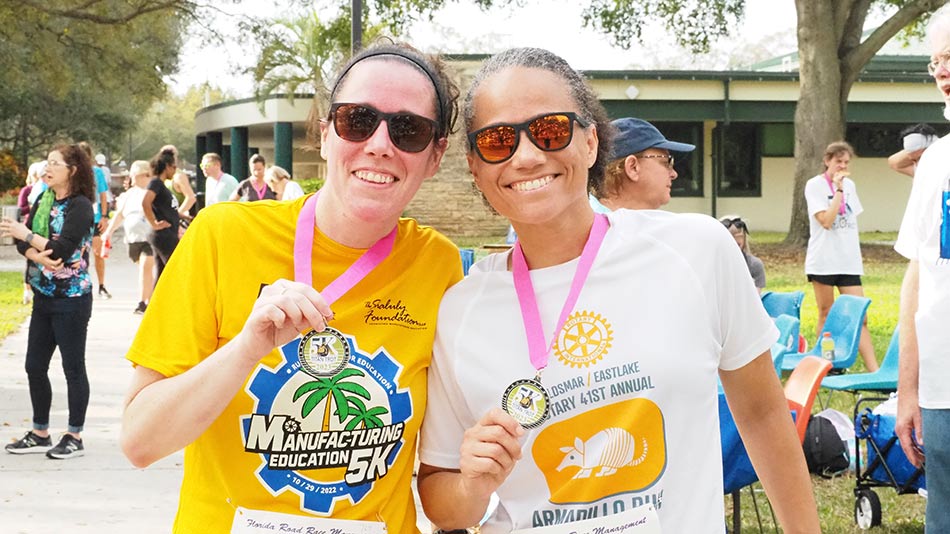 Two female runners in yellow and white tshirts with hair pulled back wearing medals they wong 