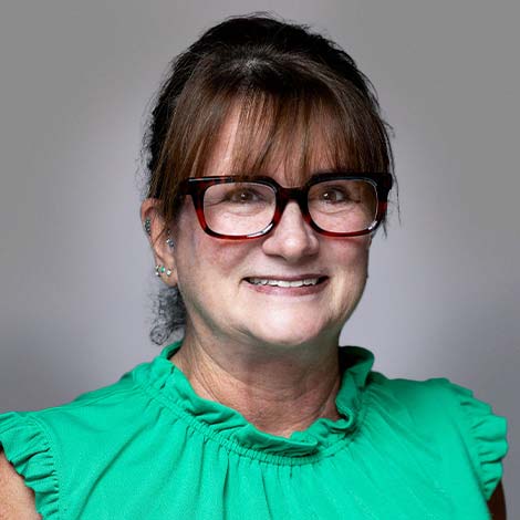 A portrait of Erica Moulton wearing glasses and a green blouse.