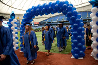 thumbnail of SPC graduates walking under an arch of blue baloons
