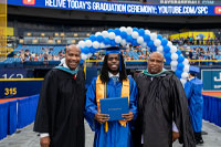 SPC student phosing for a photo with 2 male faculty in front of a blue baloon arch