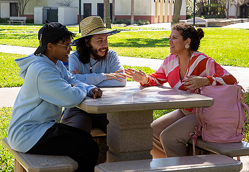 Luisa Shamas talks with two other SPC students, sitting outside at a table on the St Petersburg Gibbs campus