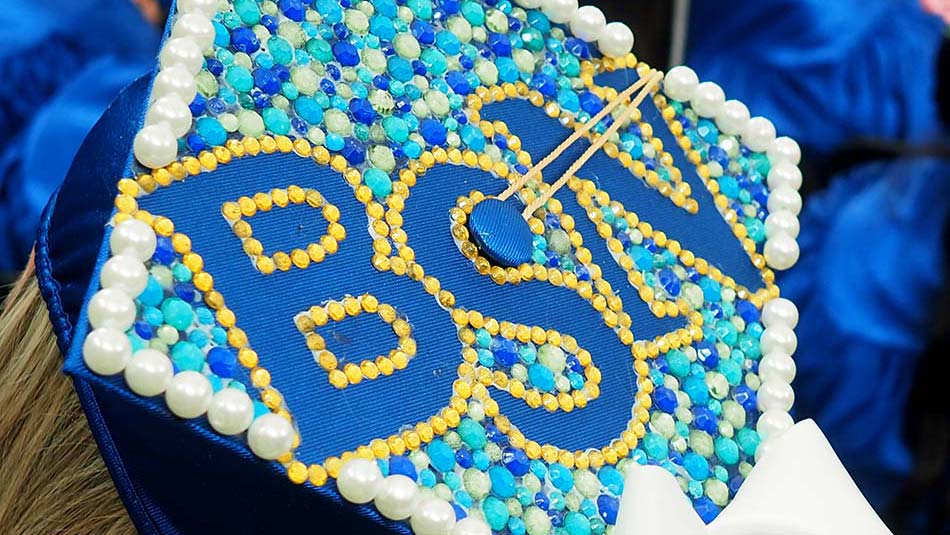 A decorated graduation cap bordered with white pearls, filled with blue, green and white beads and large, blue letters BSN (Bachelors of Science in Nursing).